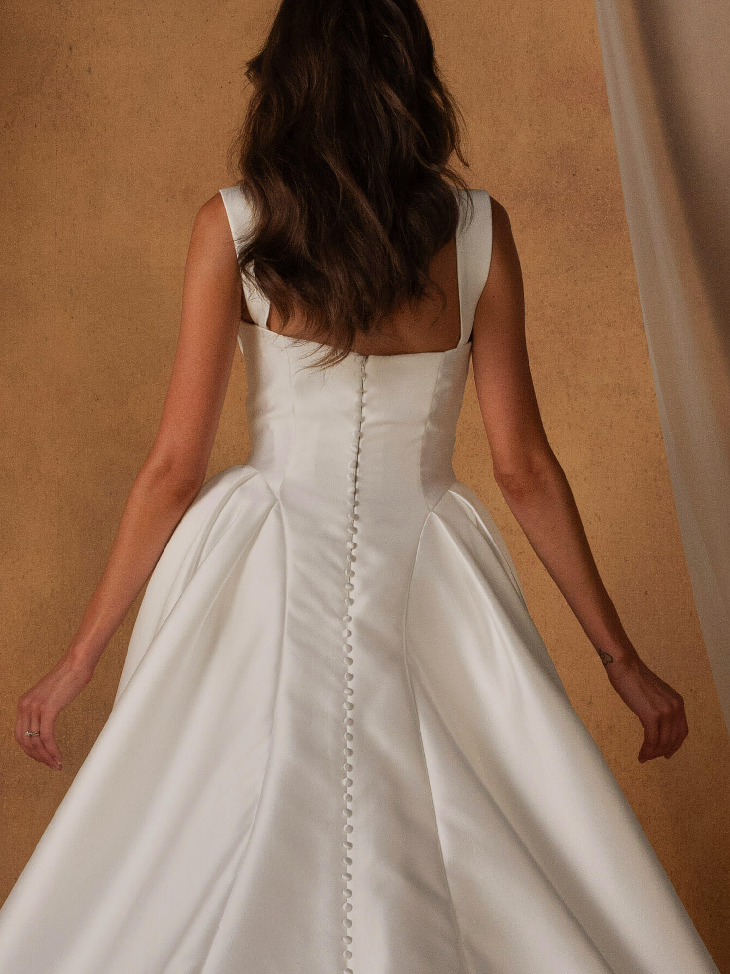 Brautkleid Rücken-Detail mit feiner Knopfleiste und tief angesetztem Rockvolumen, edler Satin-Look für deine Hochzeit in Cuxhaven.