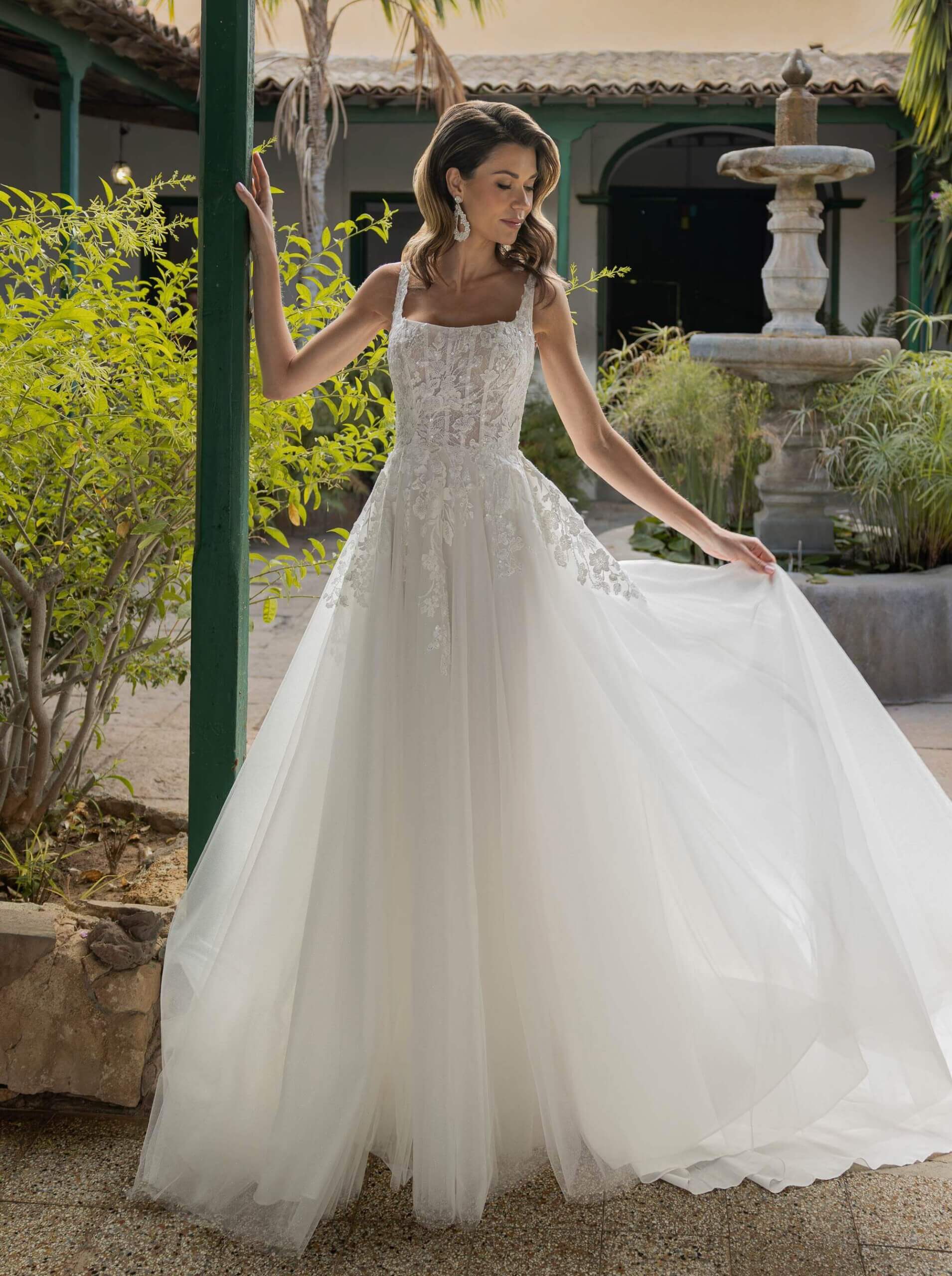 Klassisches A-Linien-Brautkleid mit eckigem Ausschnitt (Square Neck), Korsagen-Oberteil aus floraler Spitze und weitem Tüllrock.