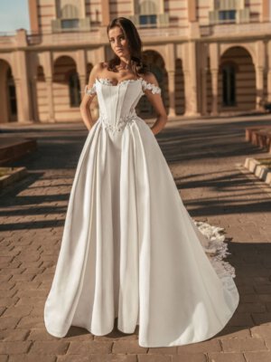 Home Ausgestelltes A-Linien-Brautkleid in Ivory mit glattem Korsagen-Oberteil, Carmen-Trägern und voluminösem Rock aus Glitzertüll mit Schleppe. Brautmode in Cuxhaven für Kundinnen aus Oldenburg und Bremen.