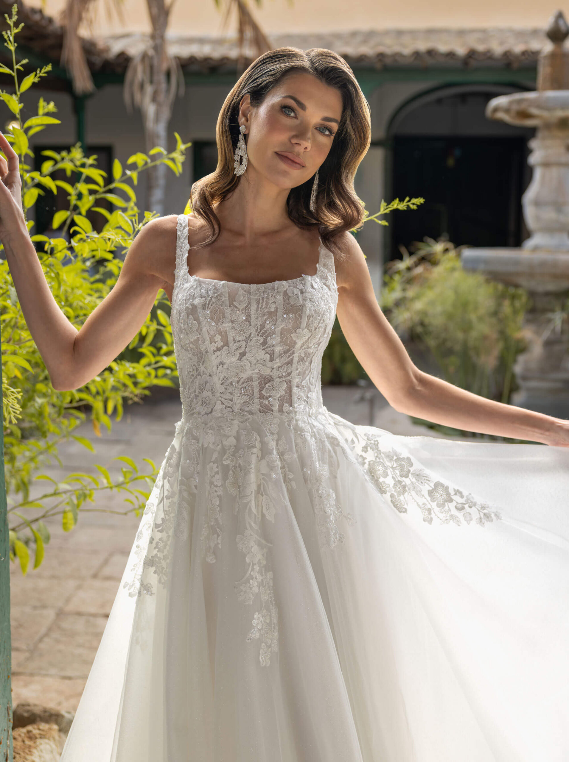 Klassisches A-Linien-Brautkleid mit eckigem Ausschnitt (Square Neck), Korsagen-Oberteil aus floraler Spitze und weitem Tüllrock.