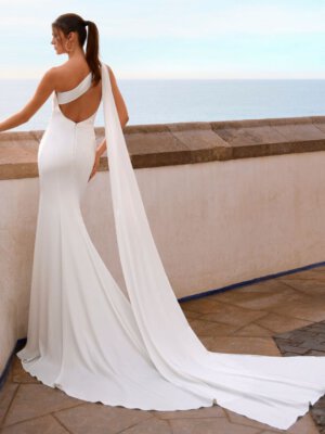 Schlichtes Fit-and-Flare-Brautkleid aus mattem Satin in Ivory, mit One-Shoulder-Ausschnitt, asymmetrischer Draperie und langer Schleppe. Angebot im Brautmodengeschäft Cuxhaven für Kundinnen aus Oldenburg und Bremen.