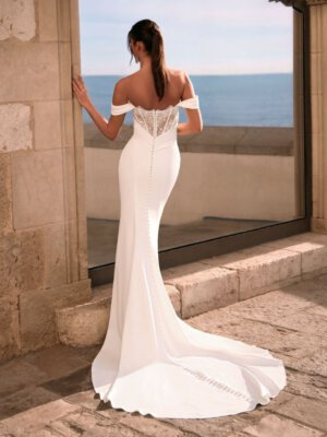 Schlichtes, figurbetontes Fit-and-Flare-Brautkleid aus mattem Satin in Ivory, mit drapiertem Korsagen-Oberteil und tief sitzenden Carmen-Trägern. Brautmode in Cuxhaven für Kundinnen aus Hamburg, Stade und Bremen.