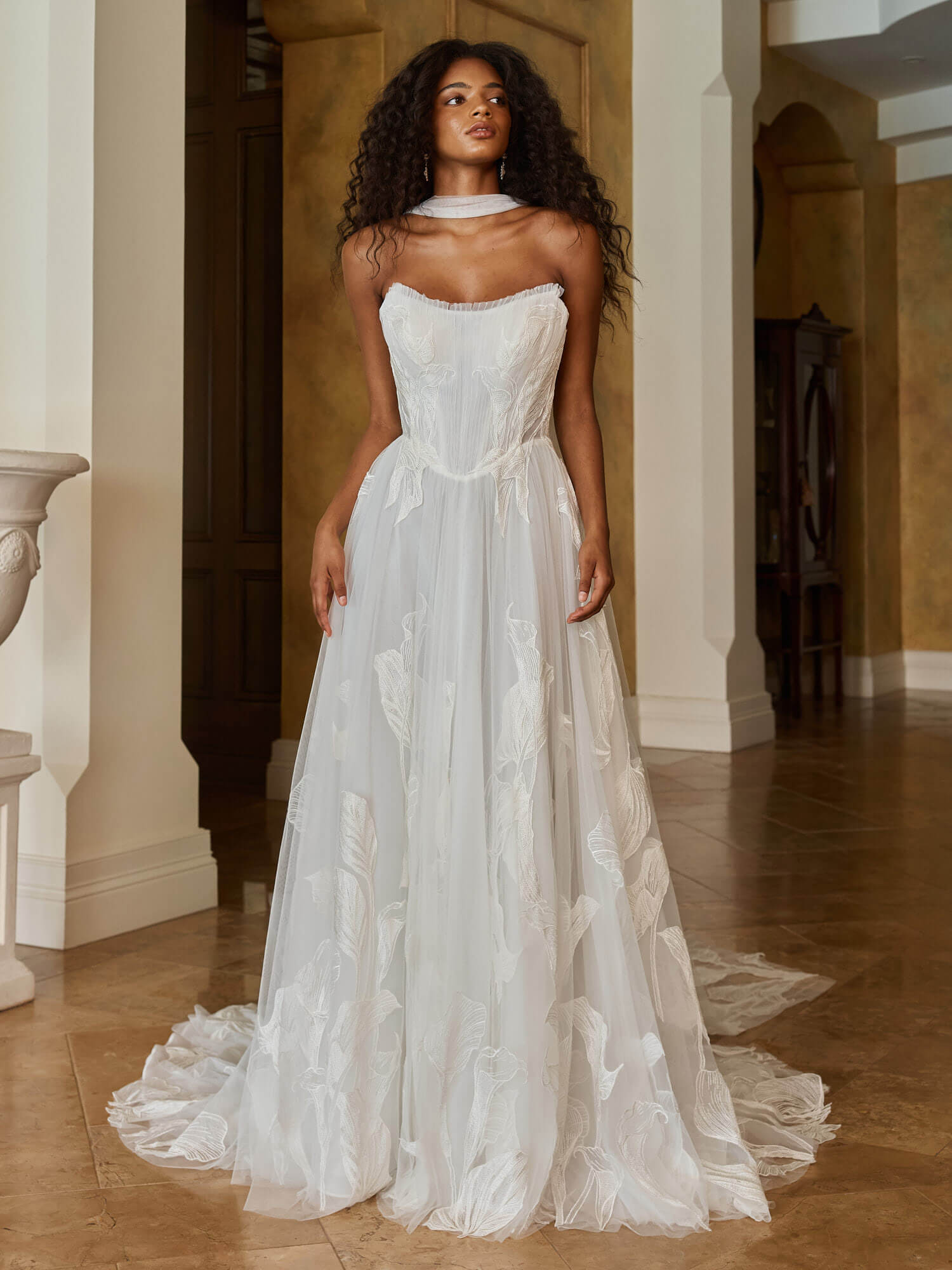 Trägerloses, weit ausgestelltes Brautkleid in Ivory mit geradem Ausschnitt, floraler Spitze am Mieder und glitzerndem Tüllrock. Hochwertige Brautmode in Cuxhaven.