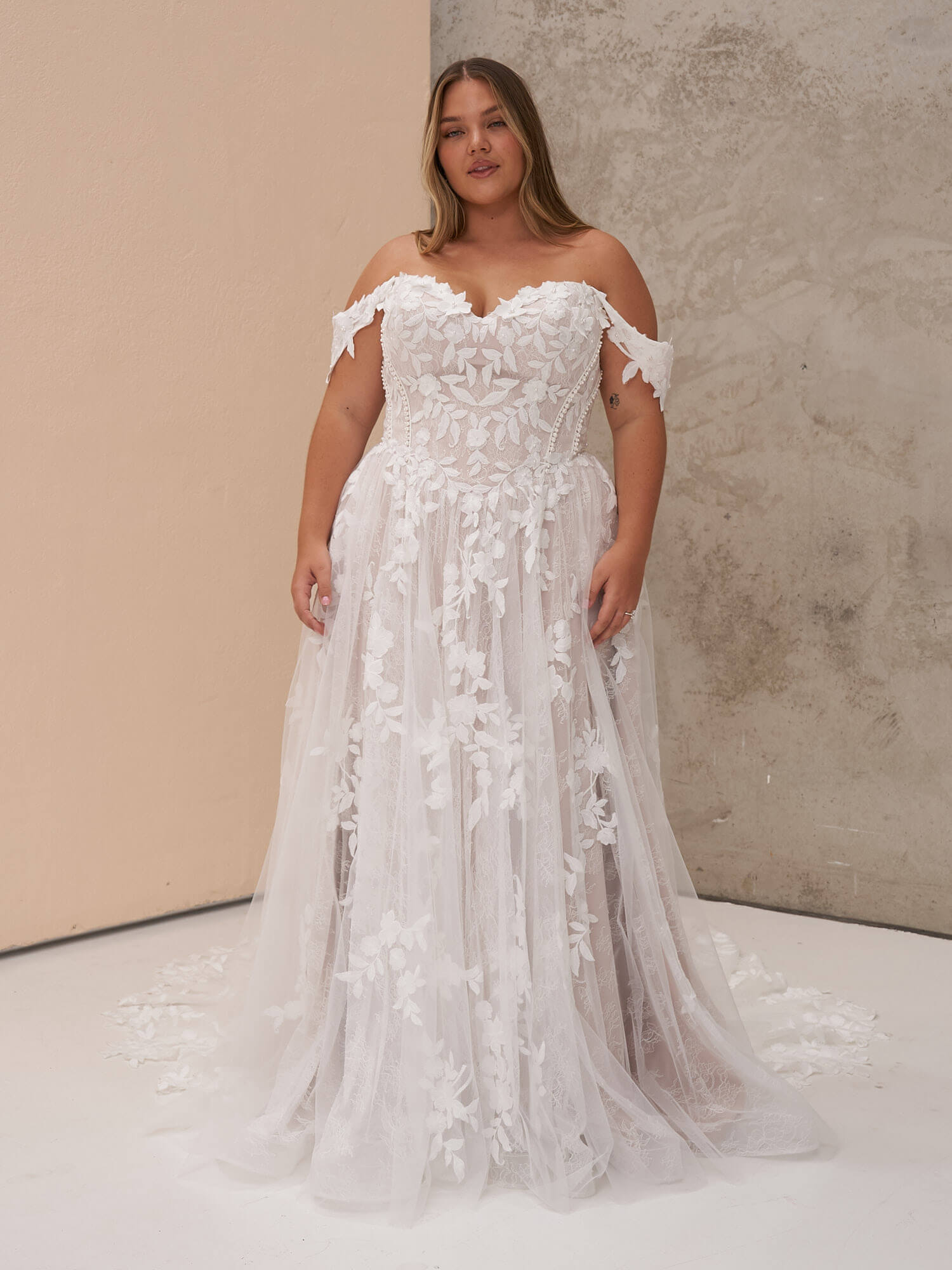 Romantisches A-Linien-Brautkleid in Ivory mit drapierten Carmen-Trägern, herzförmigem Ausschnitt und floralen Spitzenapplikationen auf dem Tüllrock. Brautmode in Cuxhaven.