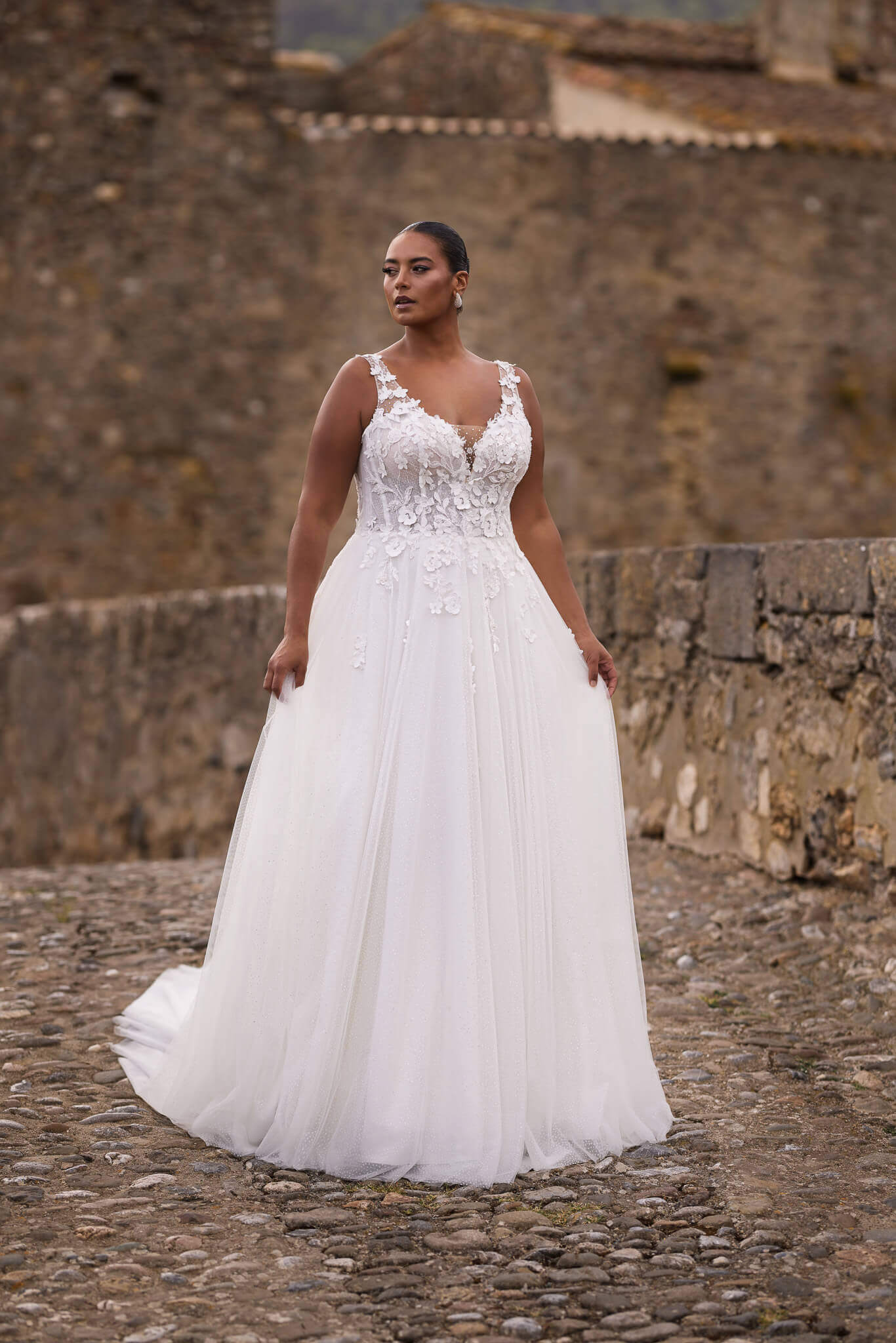 Romantisches Plus-Size-Brautkleid in fließender A-Linie mit breiten Spitzenträgern, floralen 3D-Applikationen und glitzerndem Tüllrock, exklusiv präsentiert in Cuxhaven.
