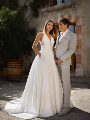 Elegantes Mikado-Brautkleid im modernen A-Linien-Stil mit tiefem V-Ausschnitt, strukturiertem Spitzenoberteil und praktischen Eingriffstaschen, exklusiv fotografiert für das Brautmodenstudio Cuxhaven.
