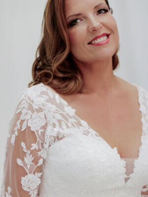 Ausgestelltes Plus-Size-Brautkleid im romantischen Stil mit halblangen Spitzenärmeln, V-Ausschnitt und weich fallendem Tüllrock, exklusiv erhältlich in Cuxhaven.