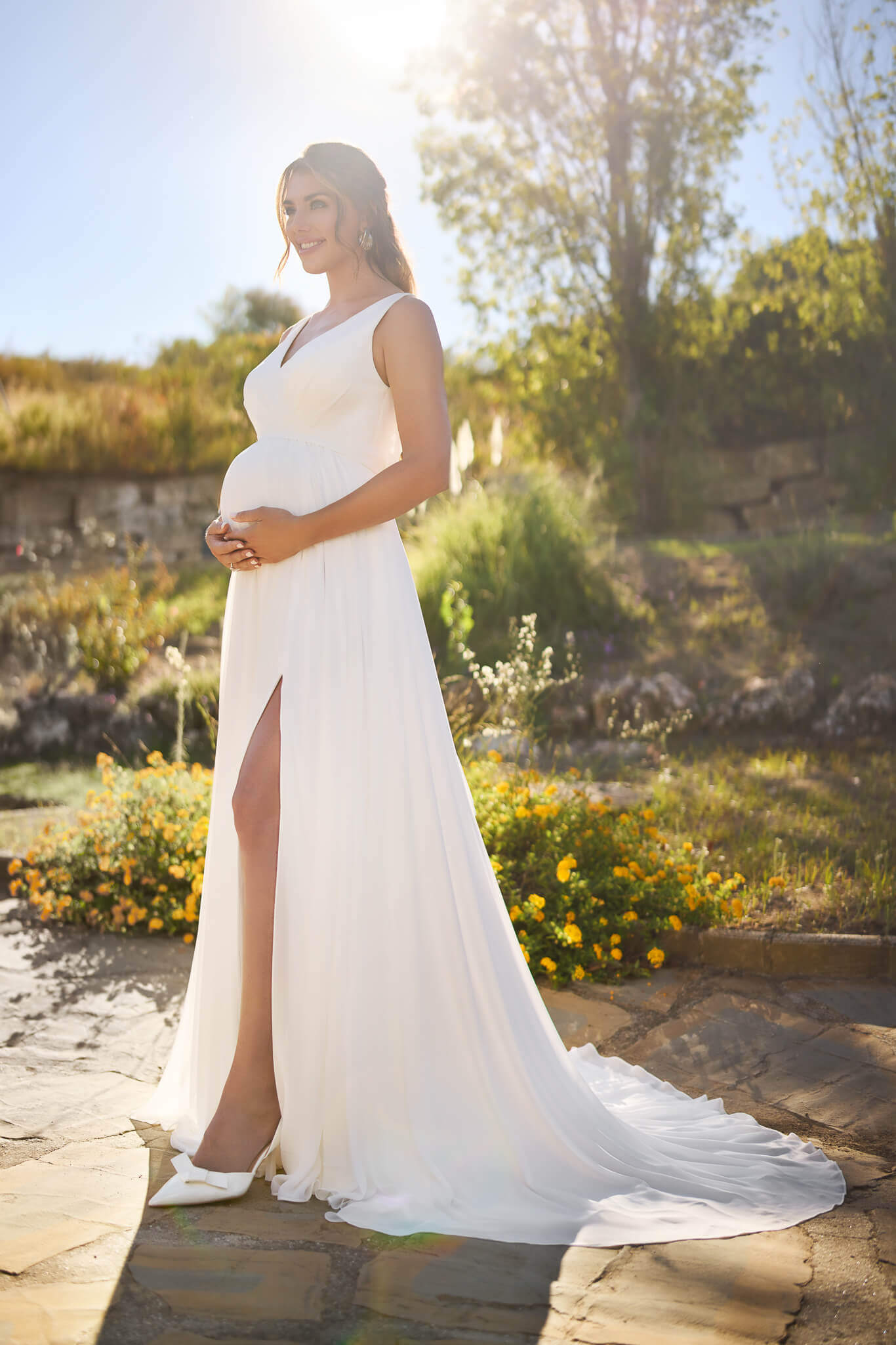 Fließendes Umstandsbrautkleid im Clean-Chic-Stil aus softem Chiffon mit V-Ausschnitt, hohem Beinschlitz und feiner Schleppe, exklusiv präsentiert im Brautmodengeschäft Cuxhaven für Schwangere aus dem Raum Bremen und Stade.