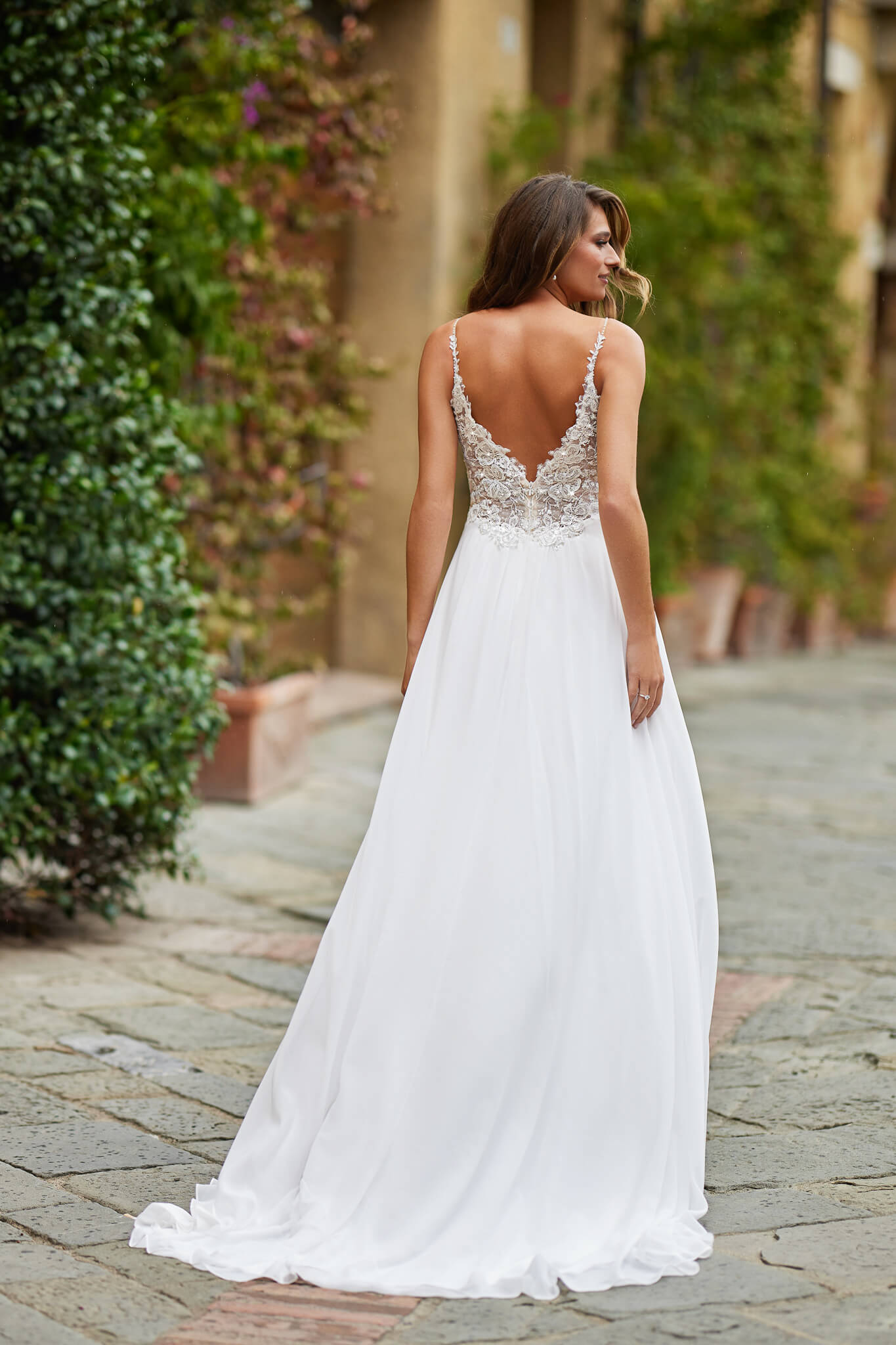Umstandsbrautkleid im romantischen Empire-Stil mit filigranen Spaghettiträgern, glitzerndem Spitzenmieder und fließendem Chiffonrock, exklusiv erhältlich in Cuxhaven.